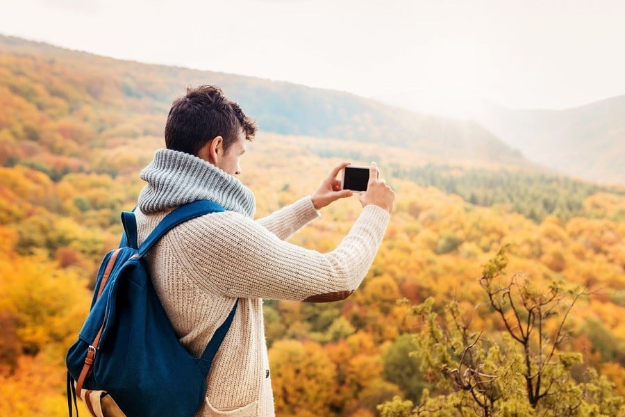 young man taking photograph in autumn