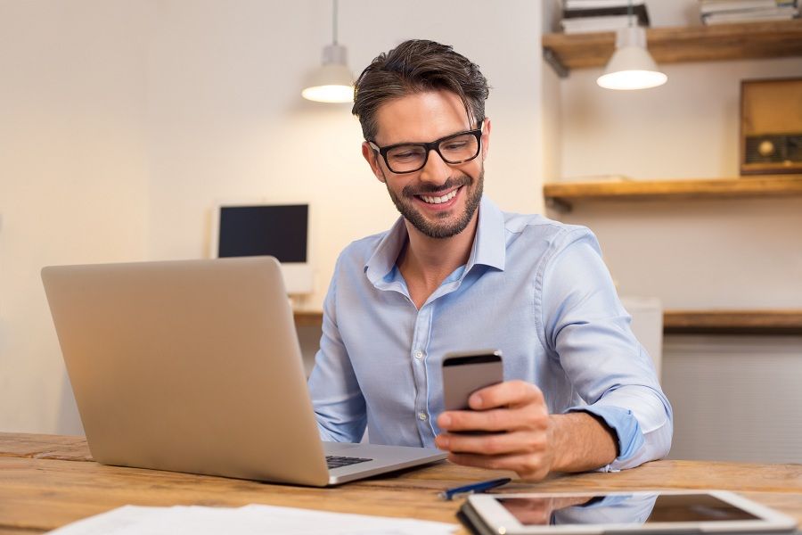 happy businessman smiling while reading his smartphone