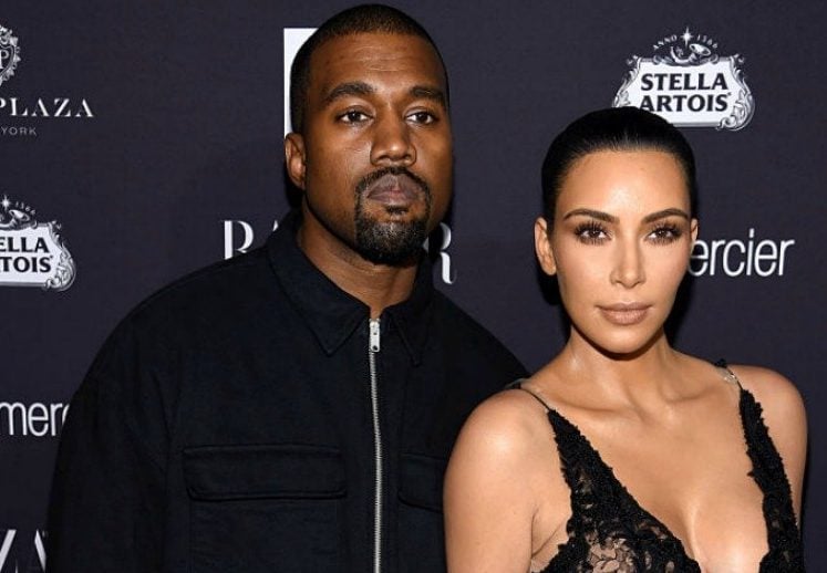 Kim and Kanye standing on a red carpet. Kim and Kanye standing on a red carpet.