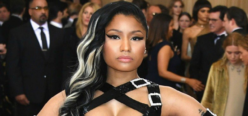 Nicki Minaj poses on the red carpet in a black and buckle dress.