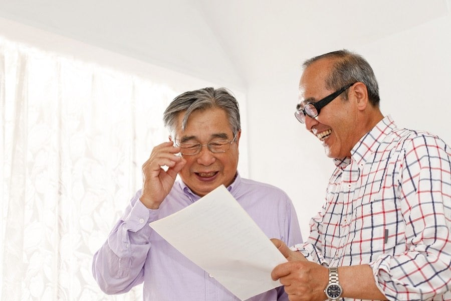 Two men laughing at a piece of paper