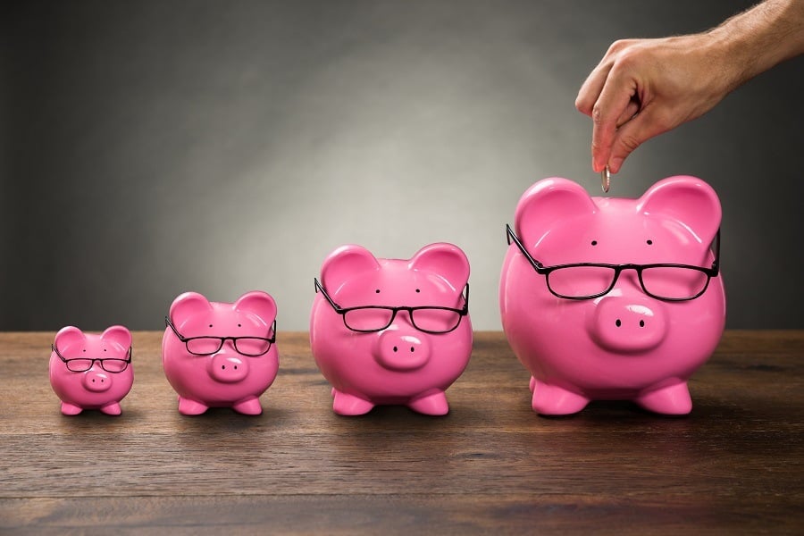 Person Hand Inserting Coin In Pink Piggybank