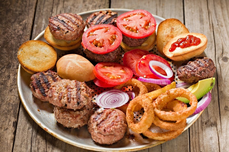 metal tray full of roasted buns, grilled miniature patties, sliced tomatoes