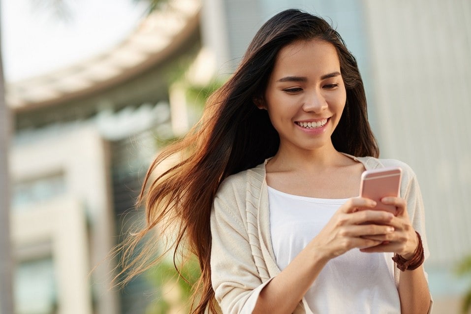Asian woman reading text messages on her smartphone