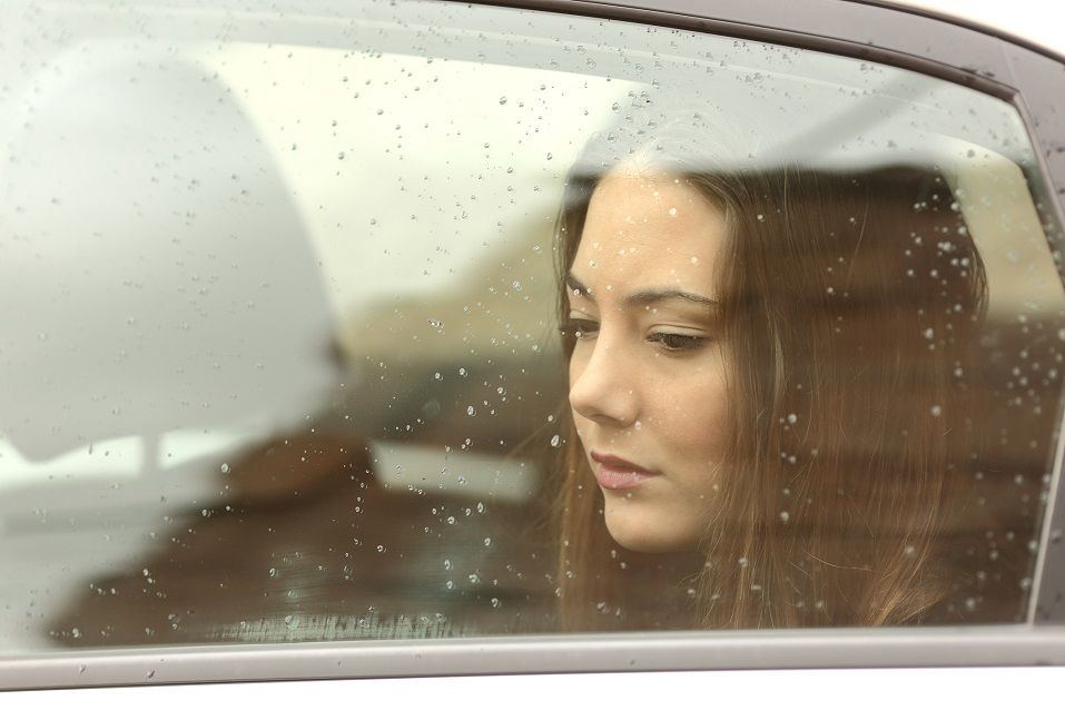 Sad woman looking down through a car window