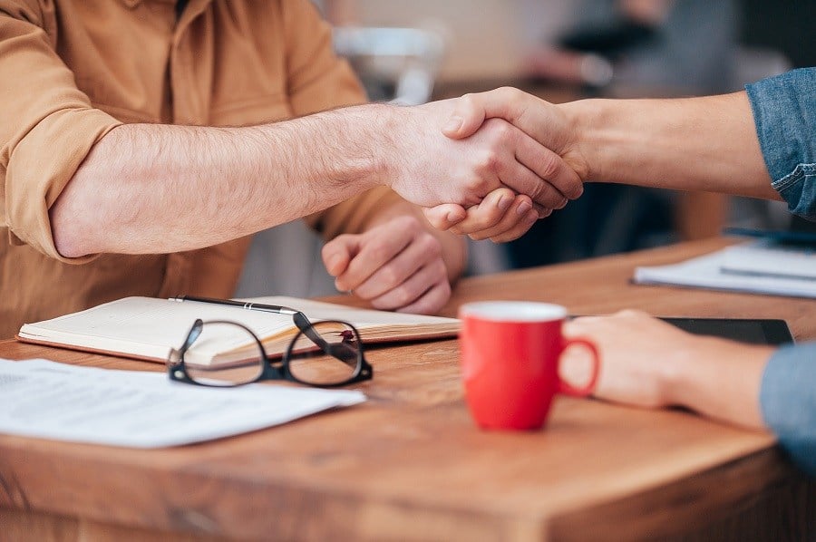 two men shaking hands over a table