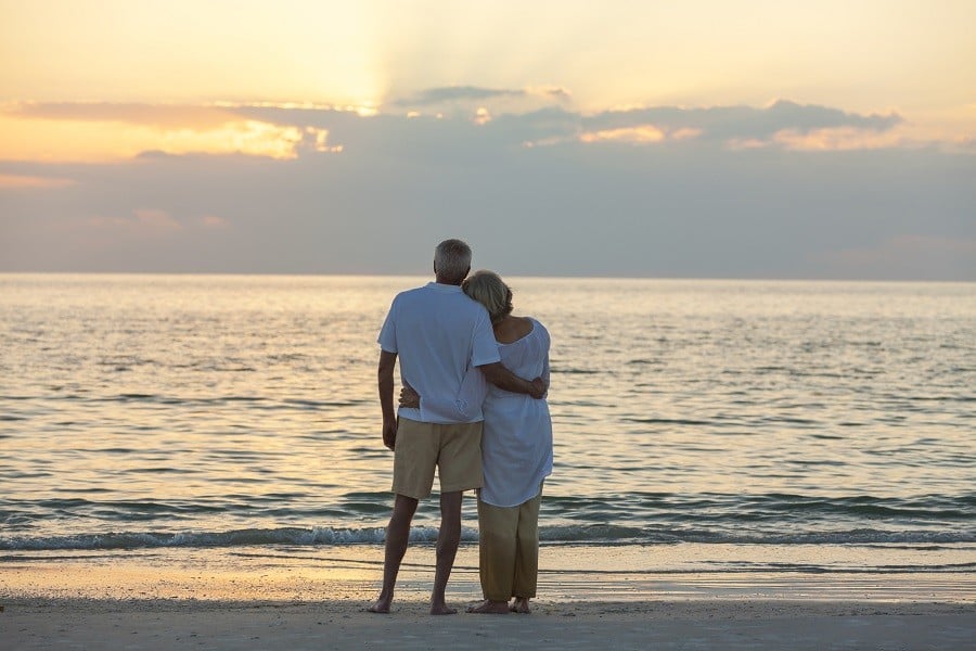 Senior man and woman couple embracing at sunset