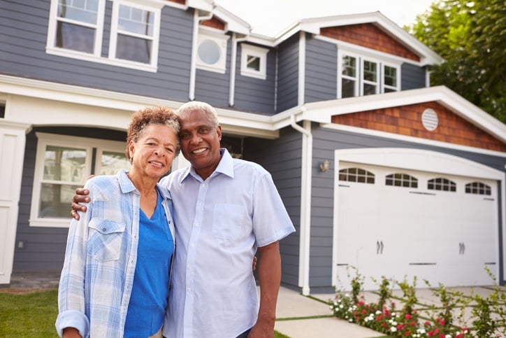 black couple standing outside a large suburban house