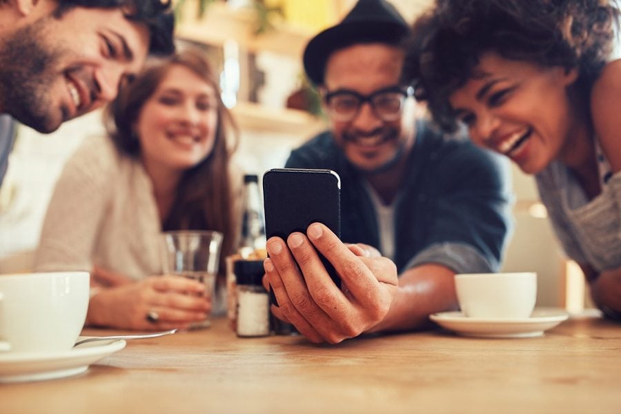 friends having fun at the cafe and looking at smart phone