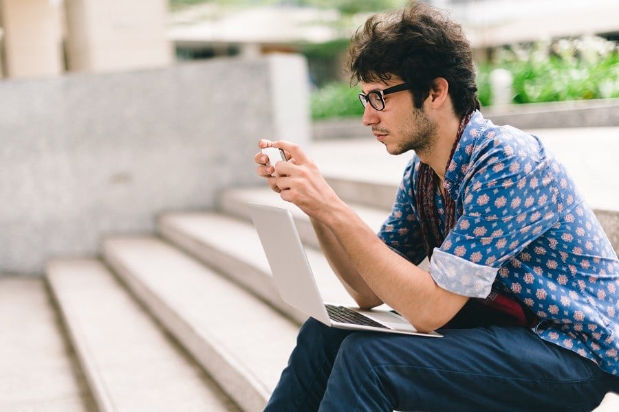 student sitting on steps and using smartphone