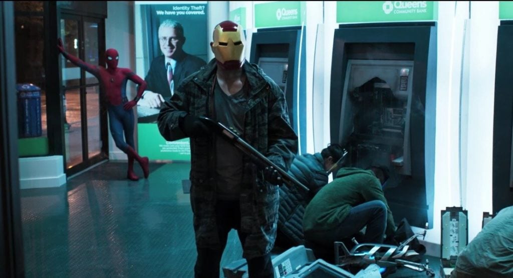 Spider-Man leans against a wall while a crew dressed as Avengers rob ATMs