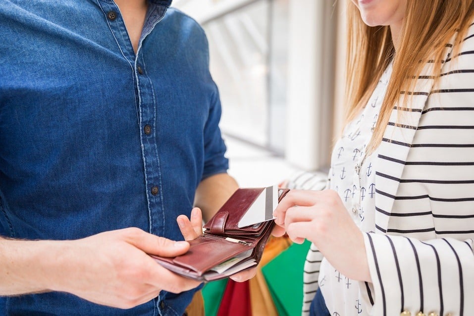 The girl is taking out a debit card from boy's wallet