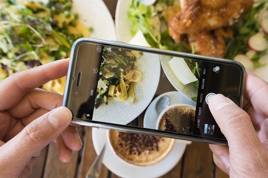 Top down view of a woman taking photo of a meal