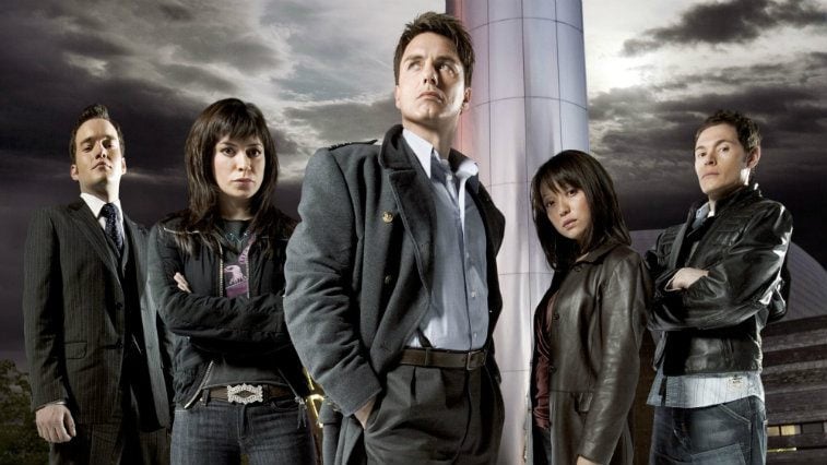 The cast of Torchwood pose under a stormy sky