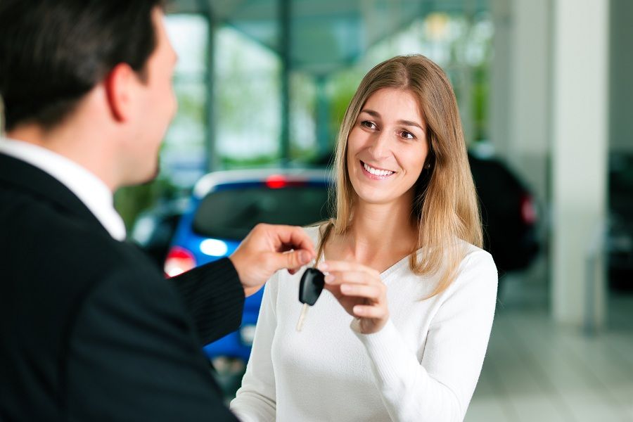 Woman taking car key from car sales rep
