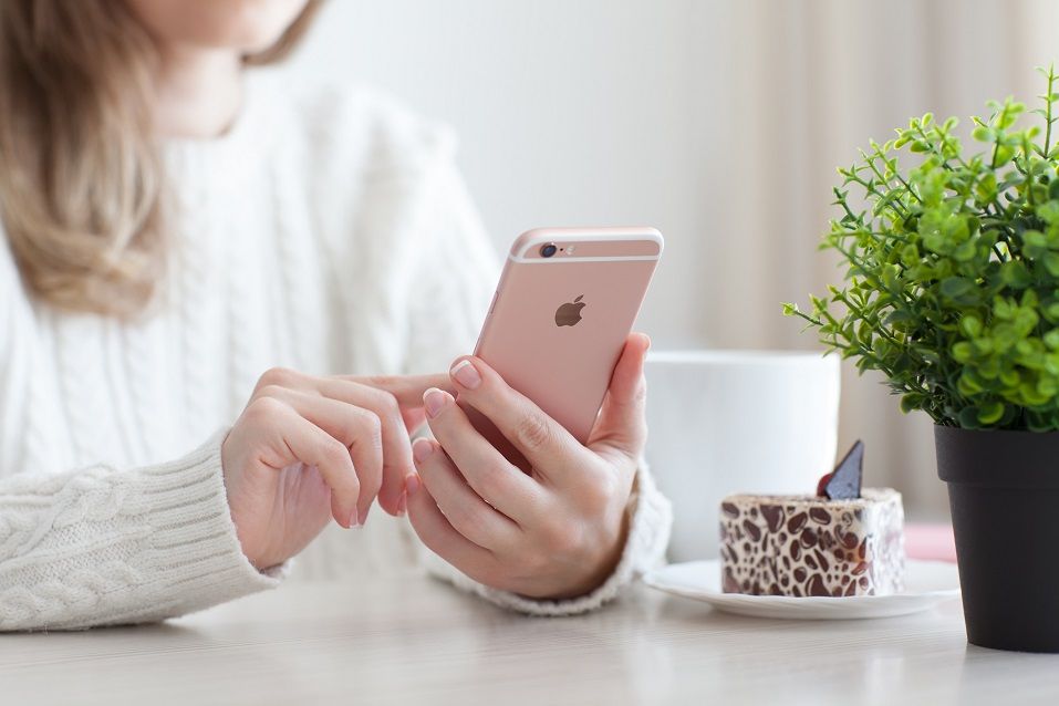 Woman holding in the hand iPhone 6 S Rose Gold in cafe