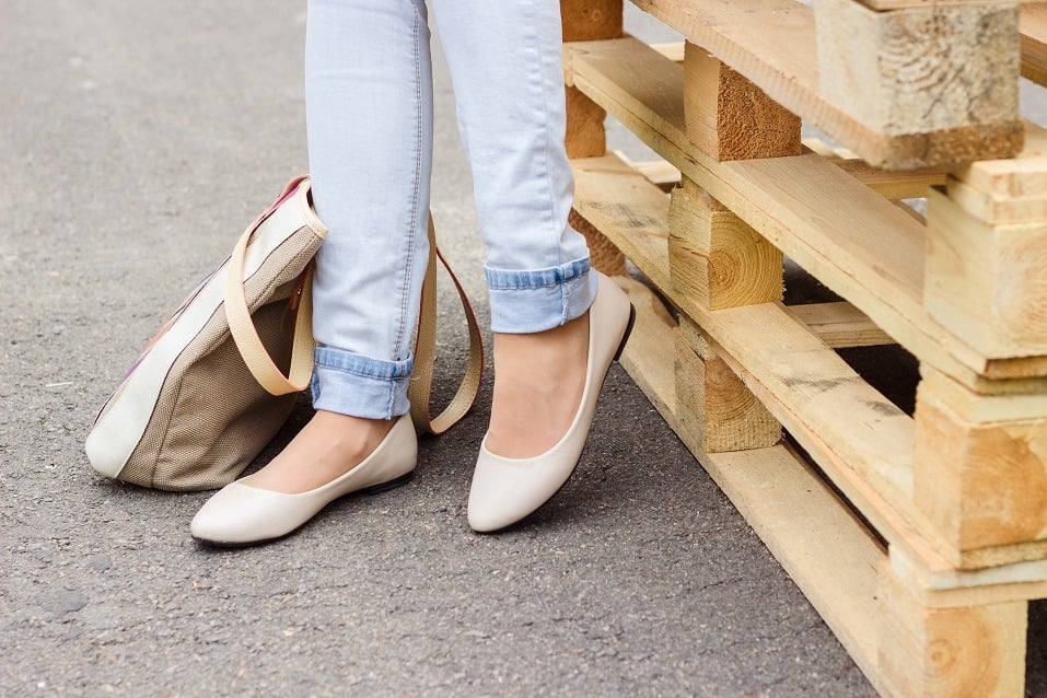 Woman's legs in jeans and white ballet flat shoes