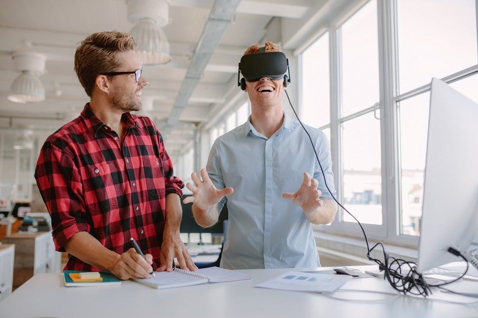 two young men testing virtual reality glasses in office