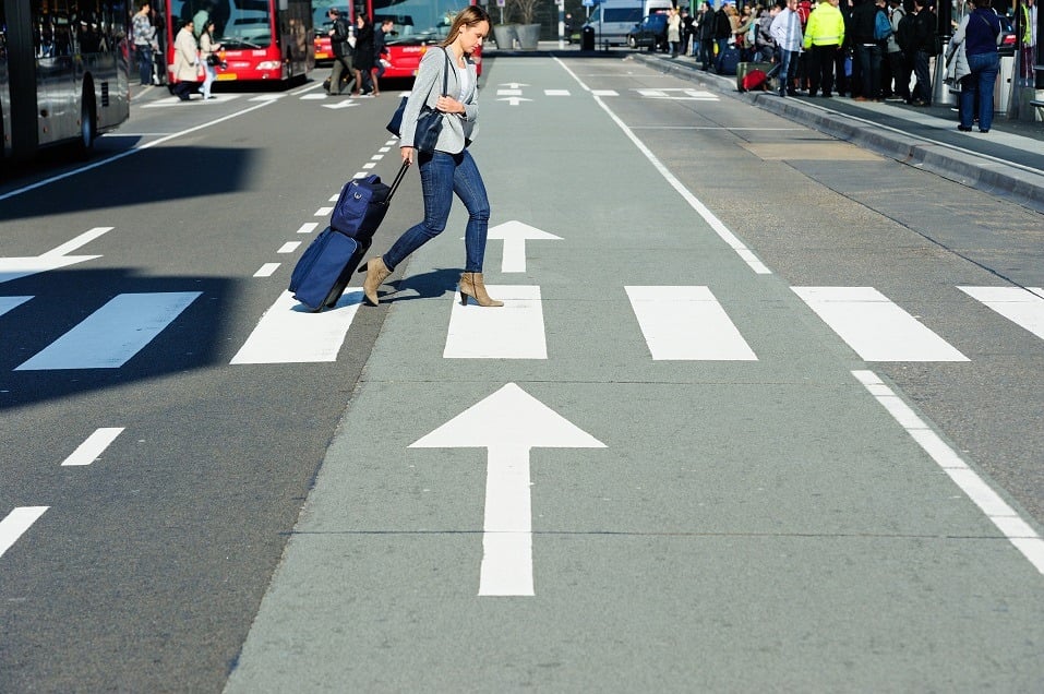 Young business traveller with carry-on bag on zebra crossing