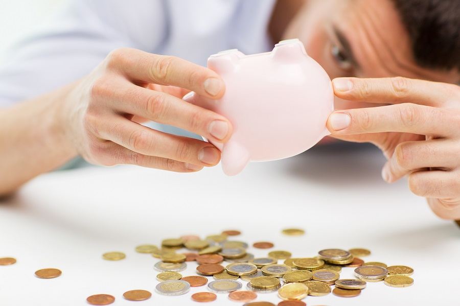 businessman pouring coins from piggy bank