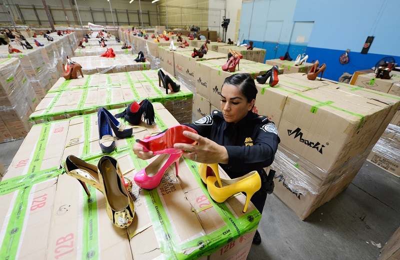 A U.S. Customs and Border Protection officer displays counterfeit designer shoes
