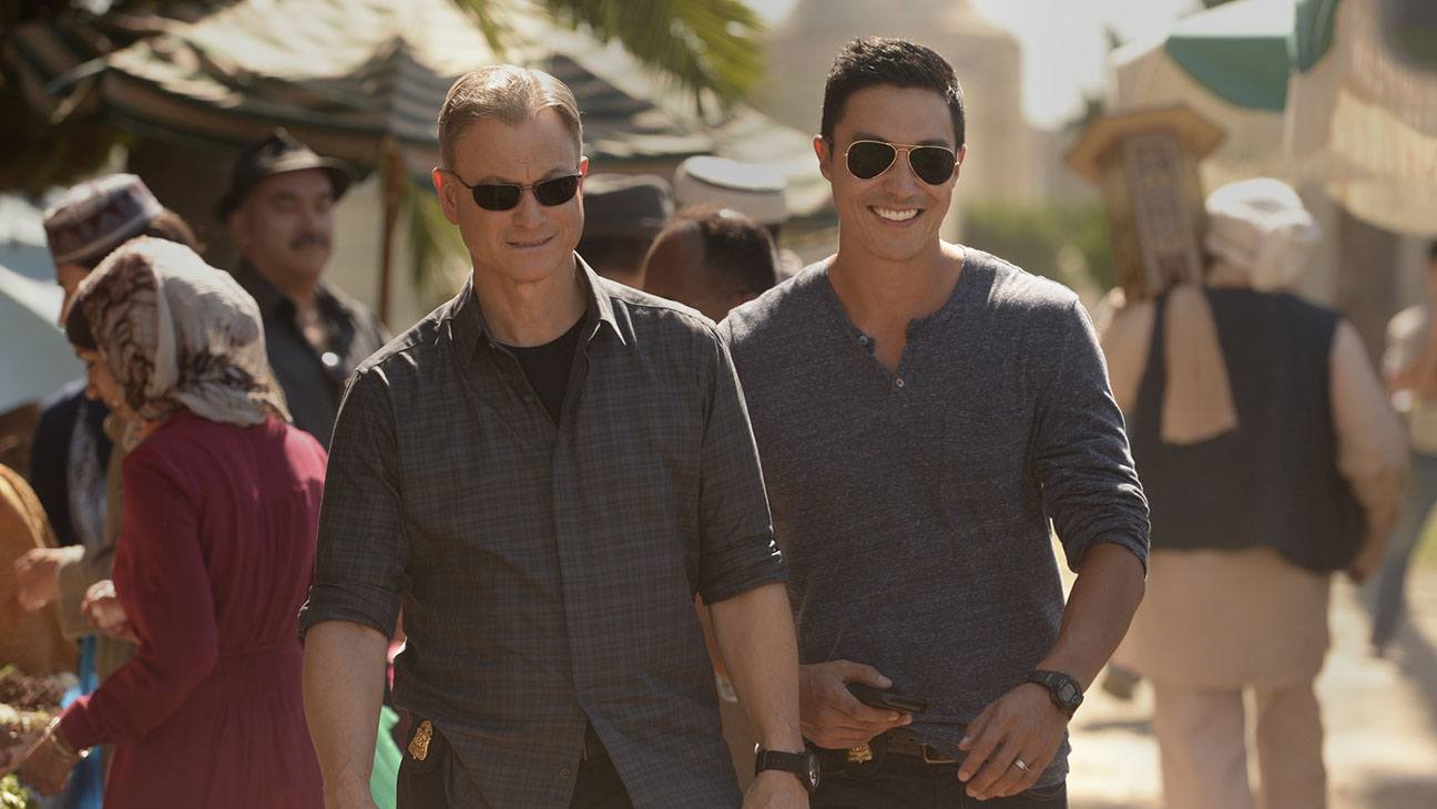 Gary Sinise and Daniel Henney walk in a busy marketplace in a scene from Criminal Minds: Beyond Borders