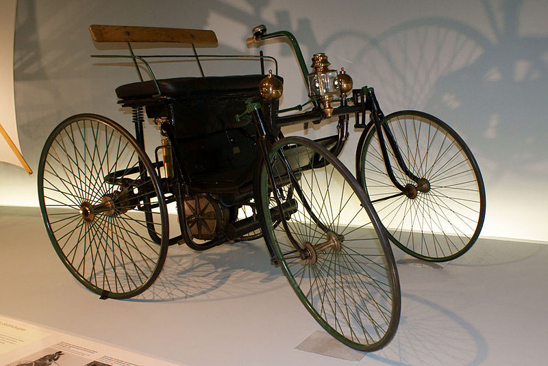One of the oldest cars in the world, the Daimler-Maybach Stahlradwagen, in a display case in a museum.