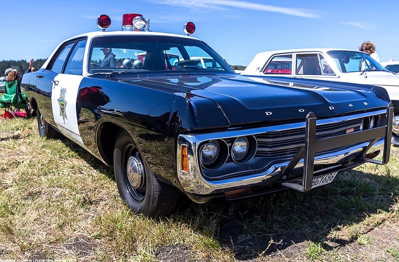 A Dodge Polara cop car parked on grass.