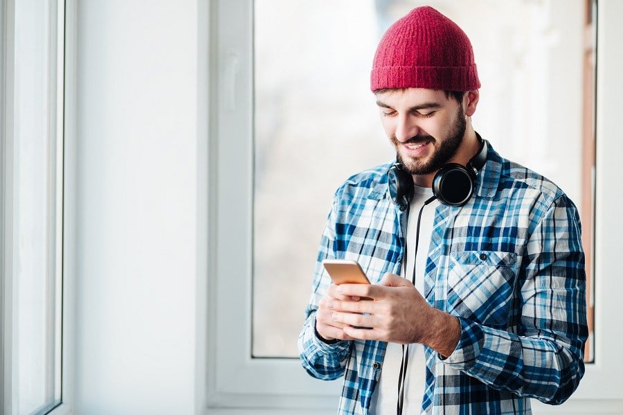 guy using a smart phone to listen music with headphones
