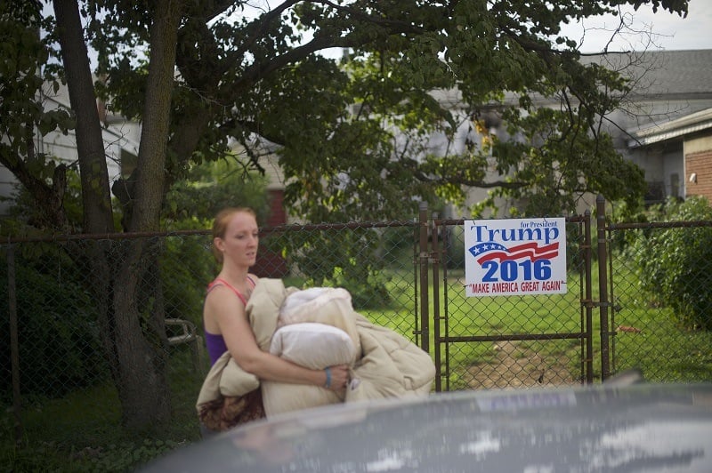 A middle class woman passes by Trump sign as she packs up her car in rural Pennsylvania