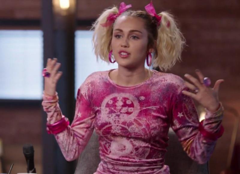 Miley Cyrus is wearing a pink shirt and pig tails on The Voice.