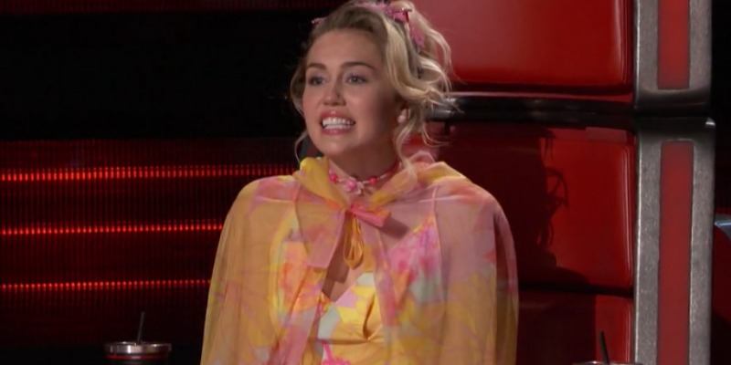 Miley Cyrus sitting the coach chair on The Voice.