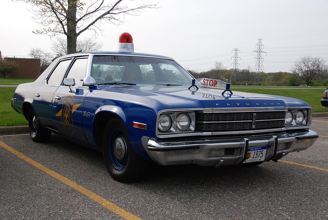 Blue Plymouth Fury cop car parked in a parking lot.