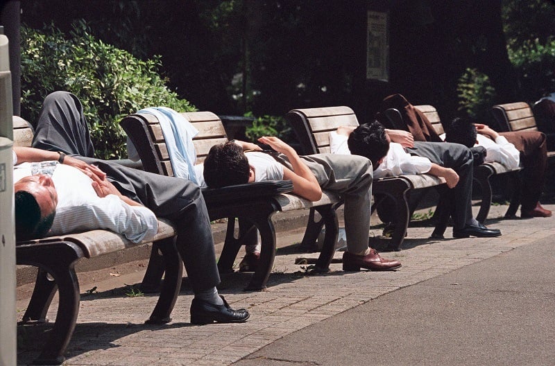 Japanese businessmen take naps on benches in Tokyo