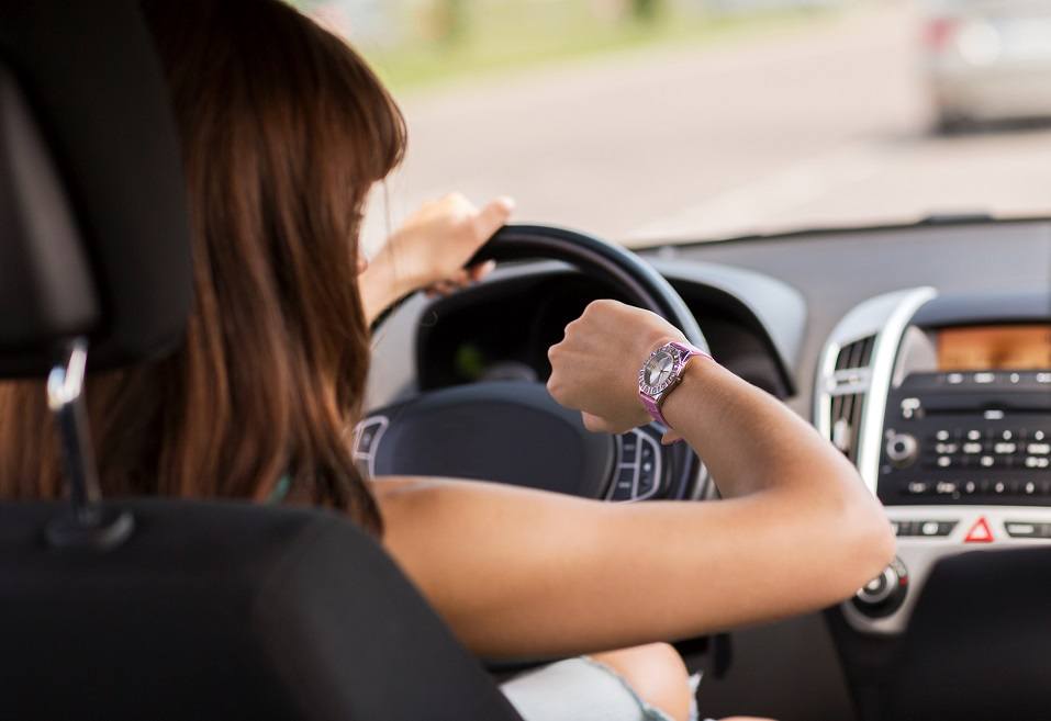 woman driving car and looking at watch