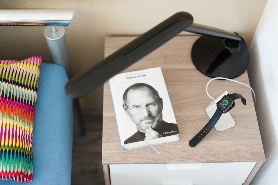 An Apple Watch is being loaded on the bedside table
