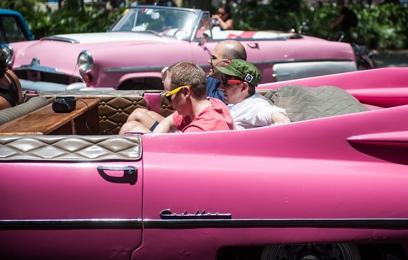 Tourists from the United States sit on an old car in Havana, on April 6, 2015. With sanctions easing, Cuba is bracing for what could be a surge in visitors that could overwhelm its small tourism industry. Americans are starting to discover Cuba, though from them, travel to the island remains limited for now to persons with Cuban relatives or those visiting in a handful of categories such as for academic, sport, religious or cultural purposes. Washington and Havana have been moving toward normalizing relations after more than 50 years of US economic sanctions and are in talks on reopening embassies.