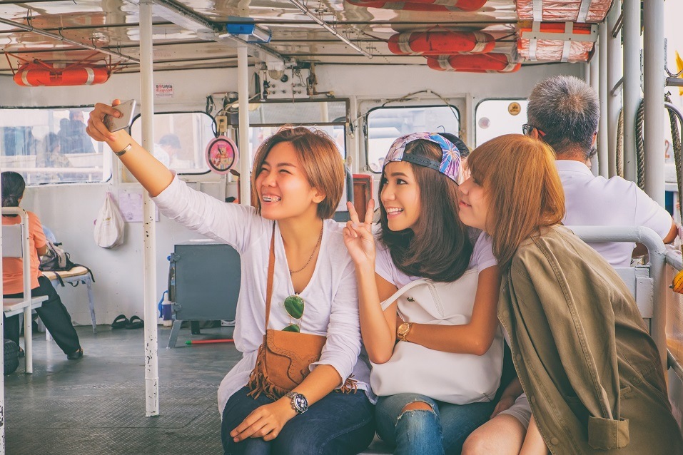 Group of happy smiling friends makes the photo while crossing the Chao Phraya River