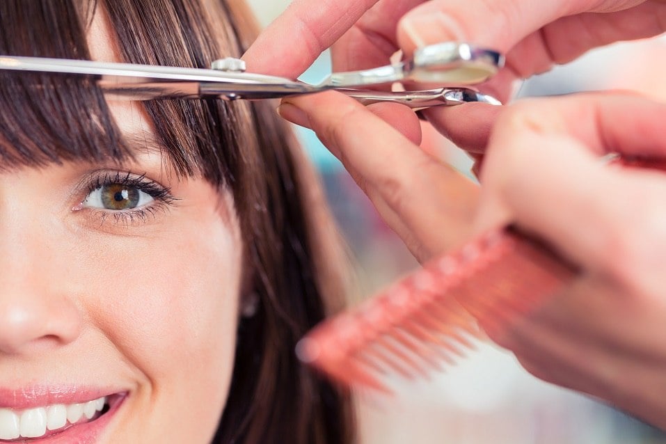Hairdresser cutting woman bangs