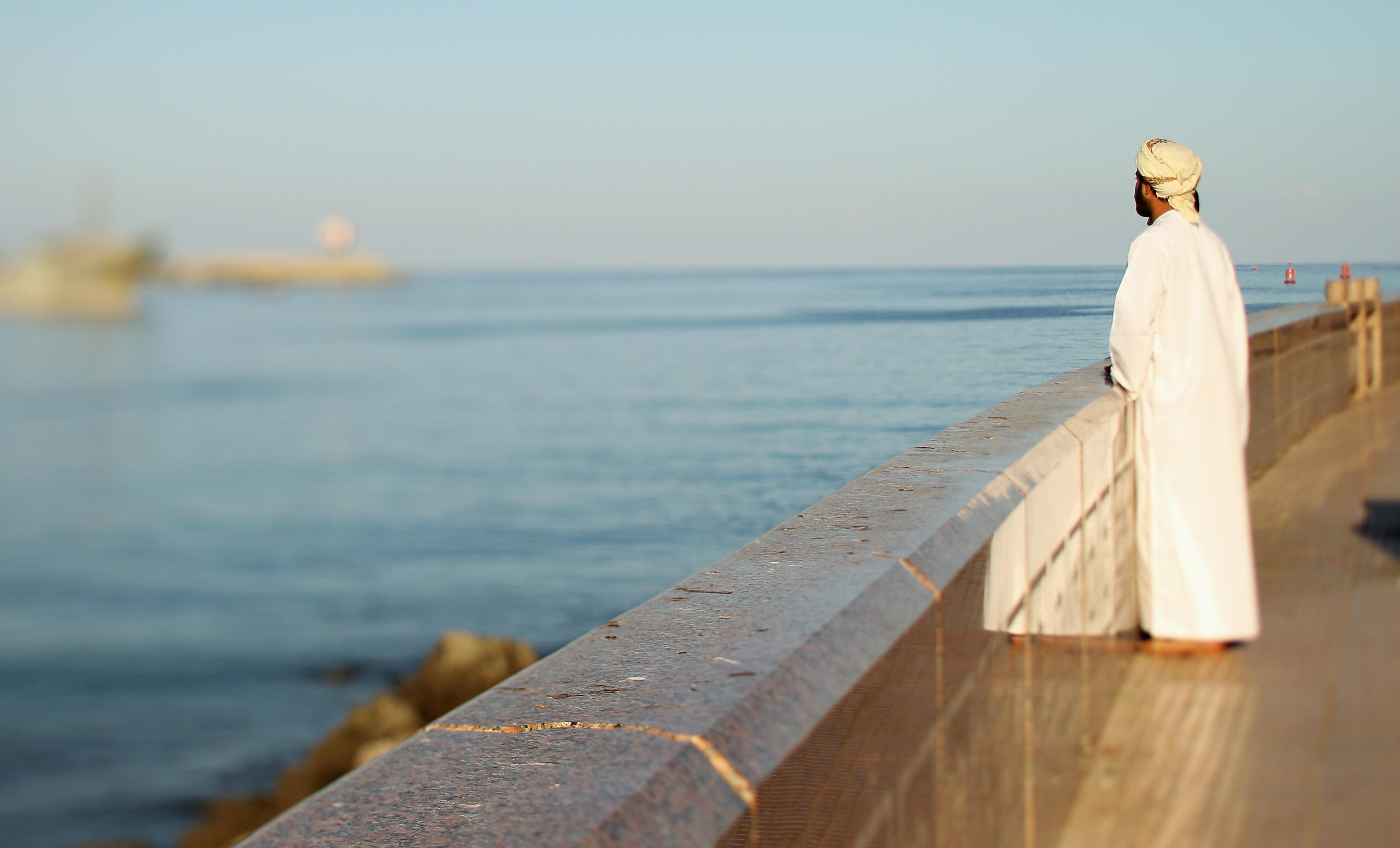 A local man looks out over Muscat harbor in Oman