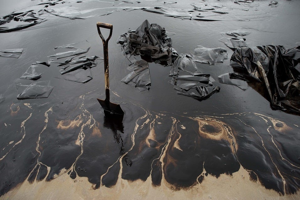 A shovel sits in oil-covered sand