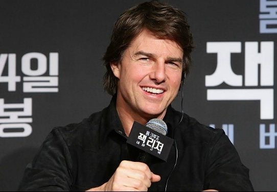 Tom Cruise holding a microphone at a press conference. Tom Cruise holding a microphone at a press conference.