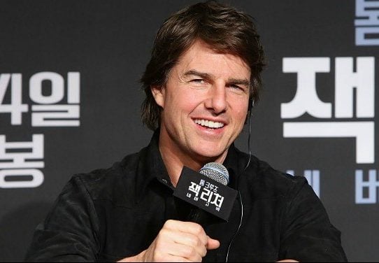 Tom Cruise holding a microphone at a press conference.