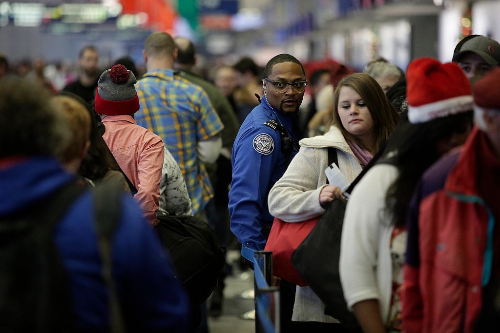 A TSA agent stands with travelers in the TSA security line at O'Hare International Airport