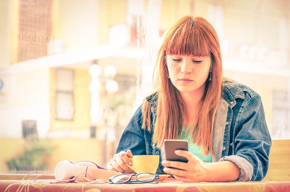 young woman with smartphone writing Instagram captions