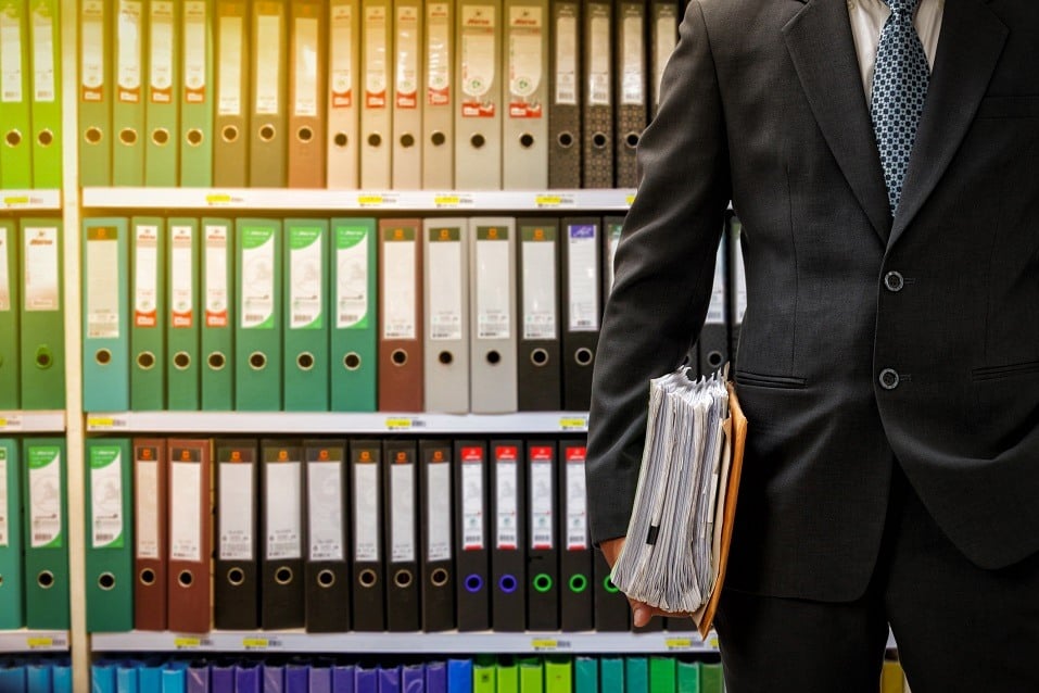 Businessman standing in front of a wall of binders