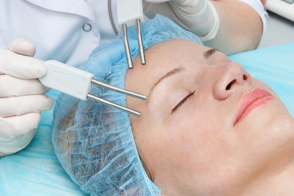 woman having microcurrent therapy by cosmetologist