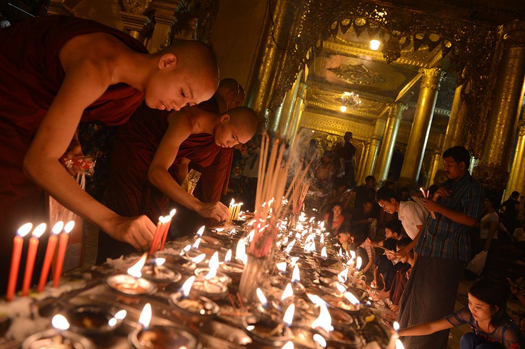 Buddhist monks lighting candles