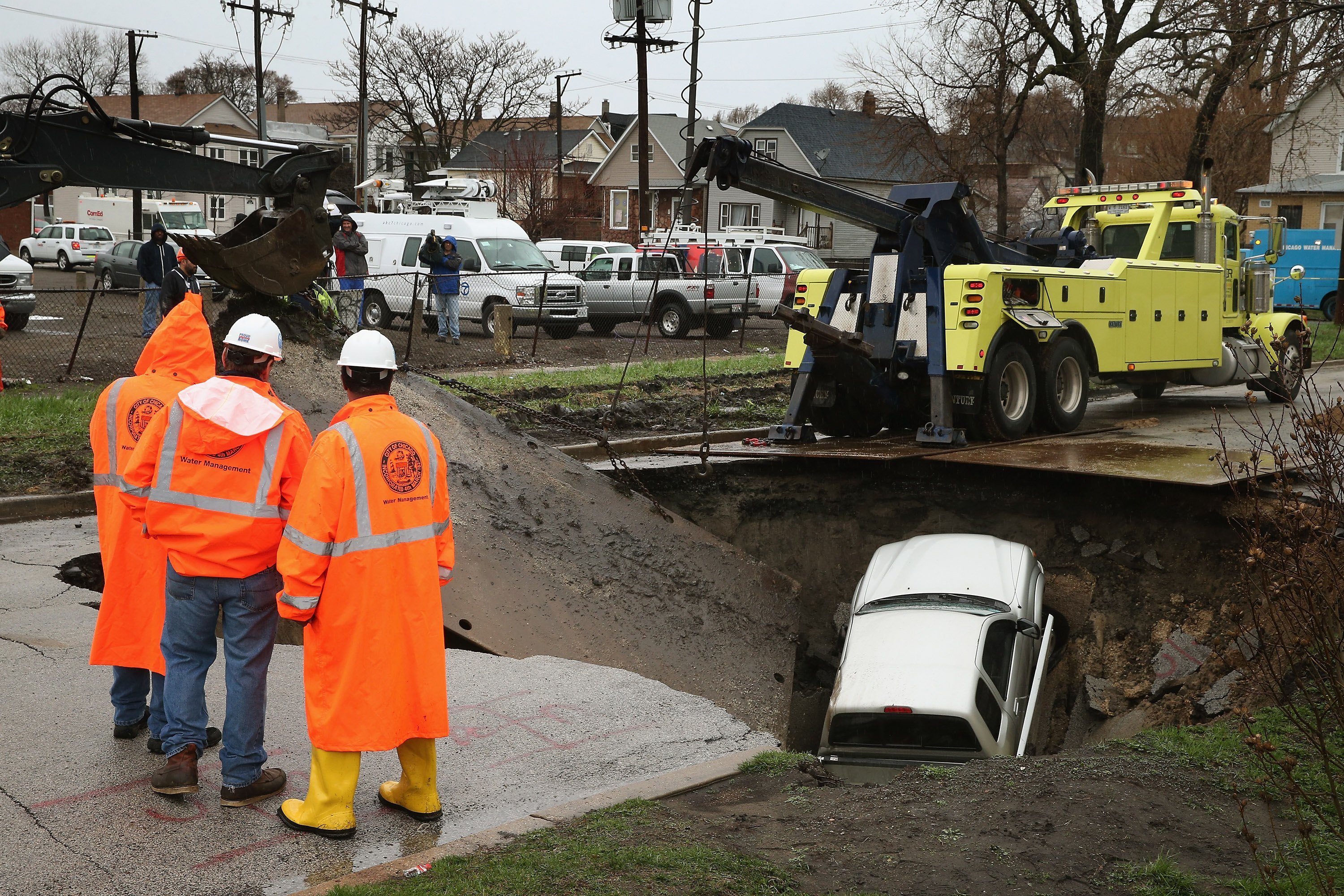 Workers prepare to pull a truck from a sinkhole
