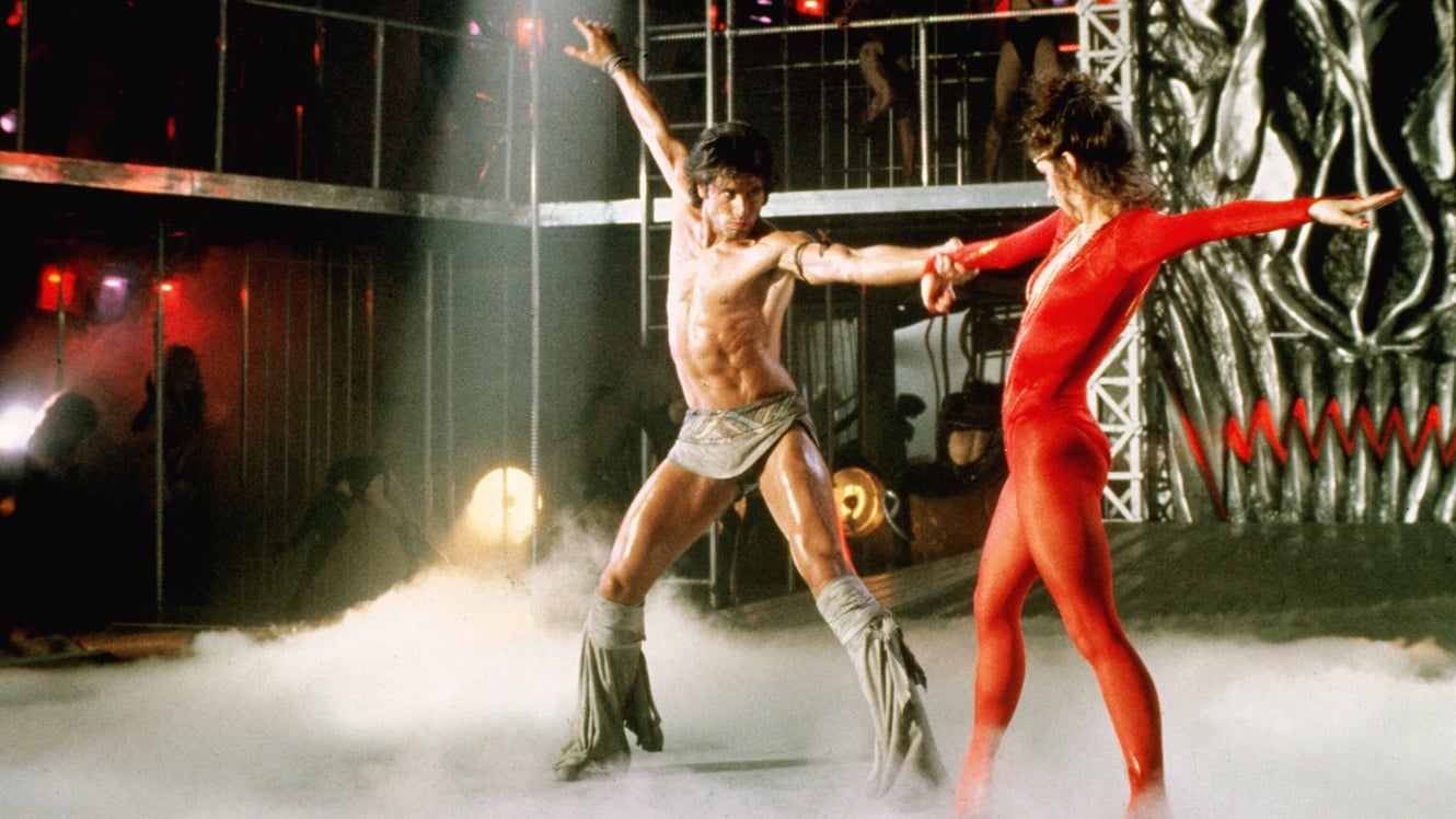 A shirtless John Travolta dances with Cynthia Rhodes on a smokey dancefloor